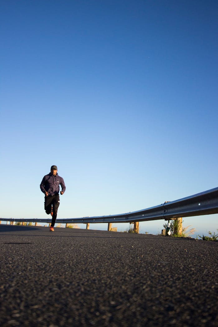 Home An athletic man jogging on an open road with a clear blue sky in Cape Town, South Africa.